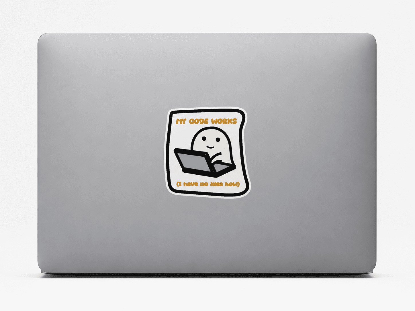 A square vinyl sticker with a cartoon ghost sitting at a laptop, displayed on the back of a silver laptop. The sticker features the text 'MY CODE WORKS' in orange at the top and 'IT HATS NOT HATS' in orange at the bottom.