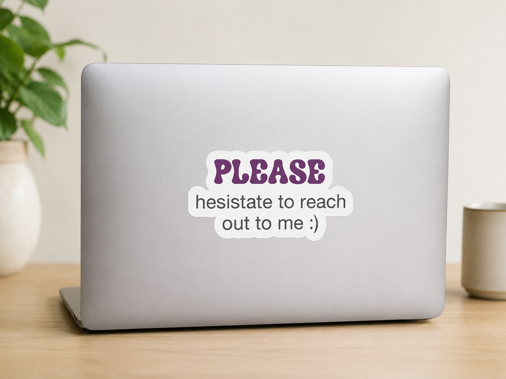 A silver laptop on a wooden desk with a white sticker that reads 'PLEASE hesitate to reach out to me :)' in purple and black text. A potted plant and a mug are blurred in the background.
