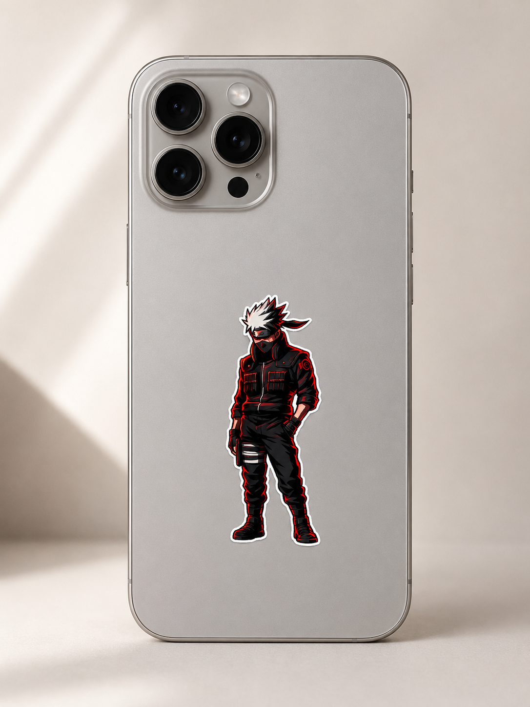 A silver phone case featuring a die-cut graphic of the anime character Kakashi Hatake, shown on a light beige background with soft shadows.